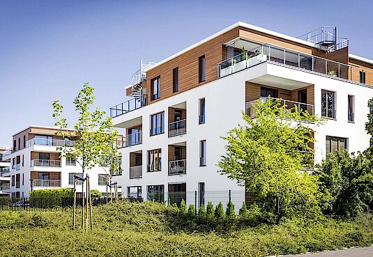 Modernes Mehrfamilienhaus mit Holzverkleidung und Bäumen im Garten