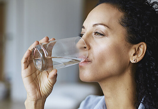 Frau trinkt Wasser aus einem Glas