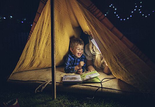 Kind mit Buch in einem Zelt